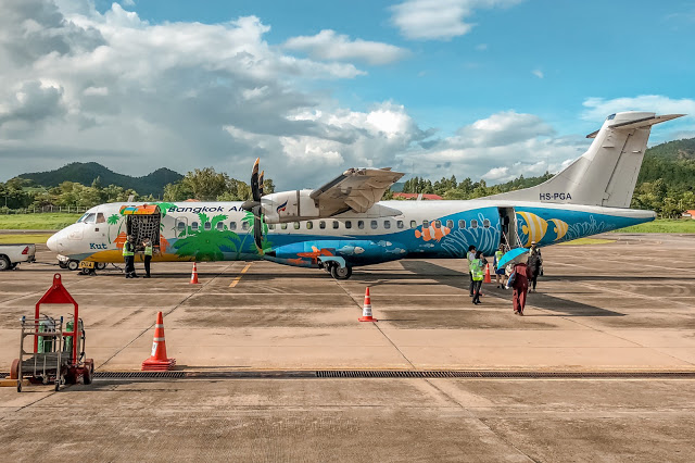 - Nếu khởi hành từ Bangkok, bạn có thể chọn đi máy bay tới Chiang Mai rồi tiếp tục đi xe khách (mất khoảng 5 - 6 tiếng) tới tỉnh Mae Hong Son. Ban Rak Thai chỉ cách Mae Hong Son khoảng 44 km.    - Nếu khởi hành từ Mae Hong Son, bạn chỉ việc chạy trên xa lộ 1095 một quãng đường dài khoảng 44 km. Lưu ý là không có trạm xăng trên đường đi nên nhớ đổ xăng trước bạn nhé, tuy nhiên cảnh vật hai bên đường rất đáng để bạn vừa lái xe vừa ngắm cảnh đấy!